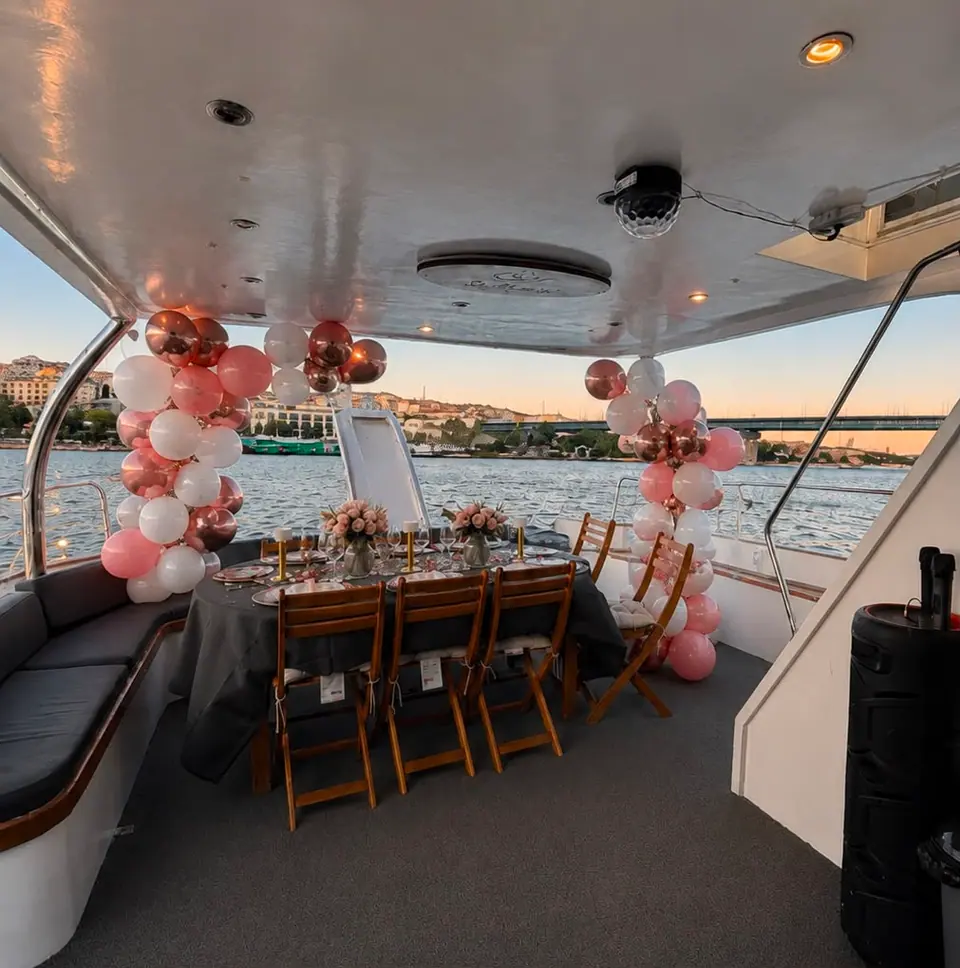 A table on deck styled with a rose gold balloon arch at sunset